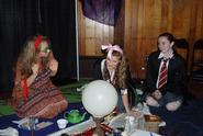 Students playing Professor Trelawney, Lavender Brown, and Parvarti Patil look into a crystal ball during Divinations class.