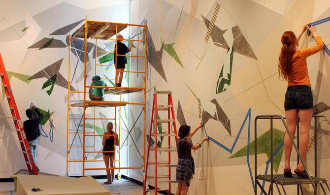 Students help artist Danielle Tegeder complete a 70-foot wall drawing in the Wellin Museum of Art.