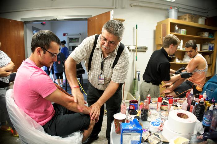 Al DePaz, of Homeland Security, applies makeup to an actor playing the role of a victim during the annual Hamilton Emergency Response Team Drill. PHOTO: NANCY FORD