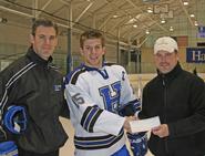 Head coach Norm Bazin (left) and team captain Joe Buicko '11 (middle) present a $1,200 check to Clinton Youth Hockey board member Todd Jury.