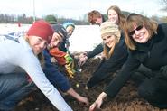 Community members, including President Joan Stewart, right, plant bulbs at the Farm Garden.