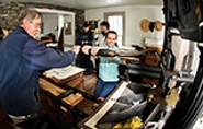 Liz Morris '16 presses an inked plate onto paper in the print shop at the Farmer's Museum with the help of Ted Shuart.