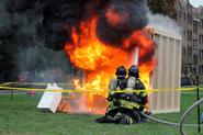 Clinton volunteer firefighters spray water on the mock dorm room fire.