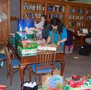 Emily Anderson '13, background left, and Laurel Emurian '11 sort holiday gifts.