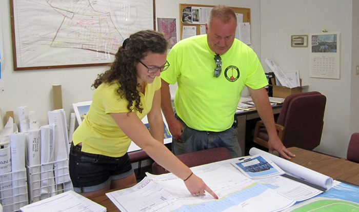 Aubrey Coon '16 reviews engineering schematics of shoreline restoration with Village of Sylvan Beach Administrator Joseph Benedict.