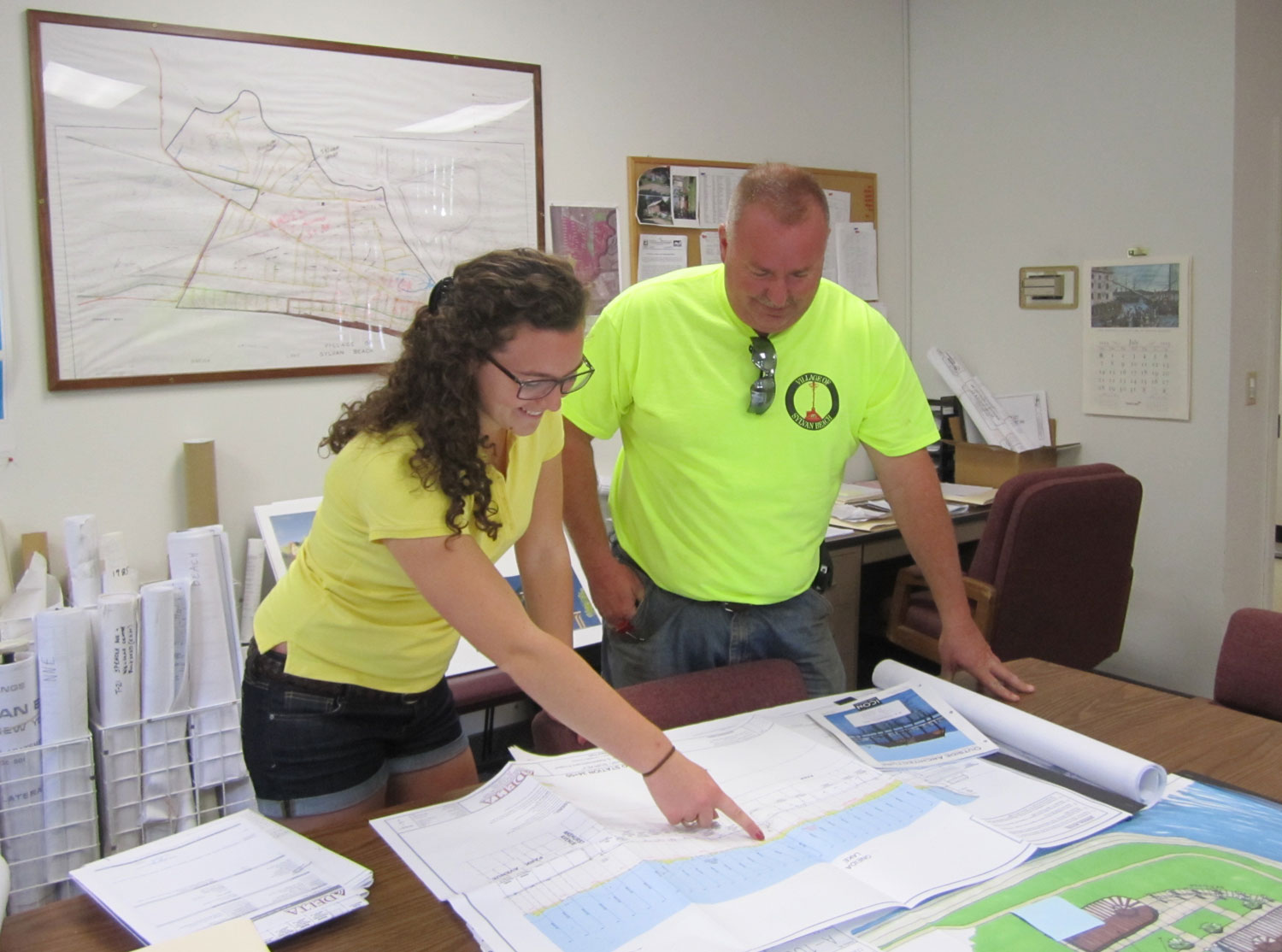 Aubrey Coon '16 reviews engineering schematics of shoreline restoration with Village of Sylvan Beach Administrator Joseph Benedict.