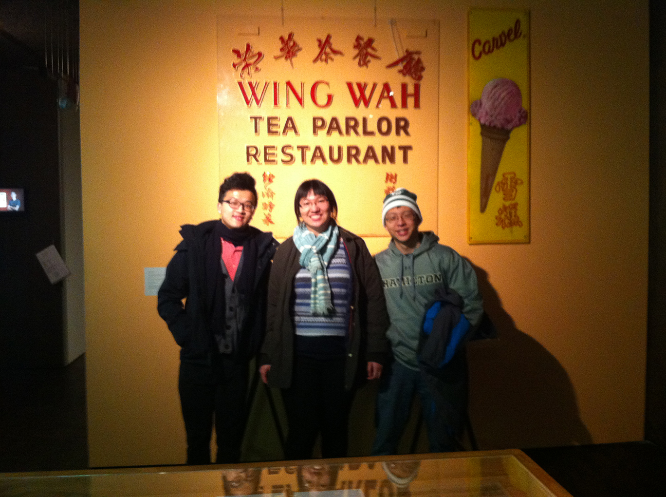 Sitong Chen '16, Jessica Tang '16, Sterling Xie '16 stand in front of a sign for a tea shop. 