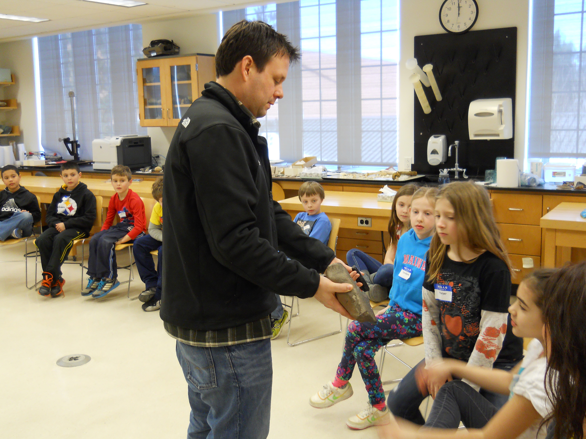 Anthropology professor Nathan Goodale shows the children igneous (volcanic) rocks called obsidian and basal.